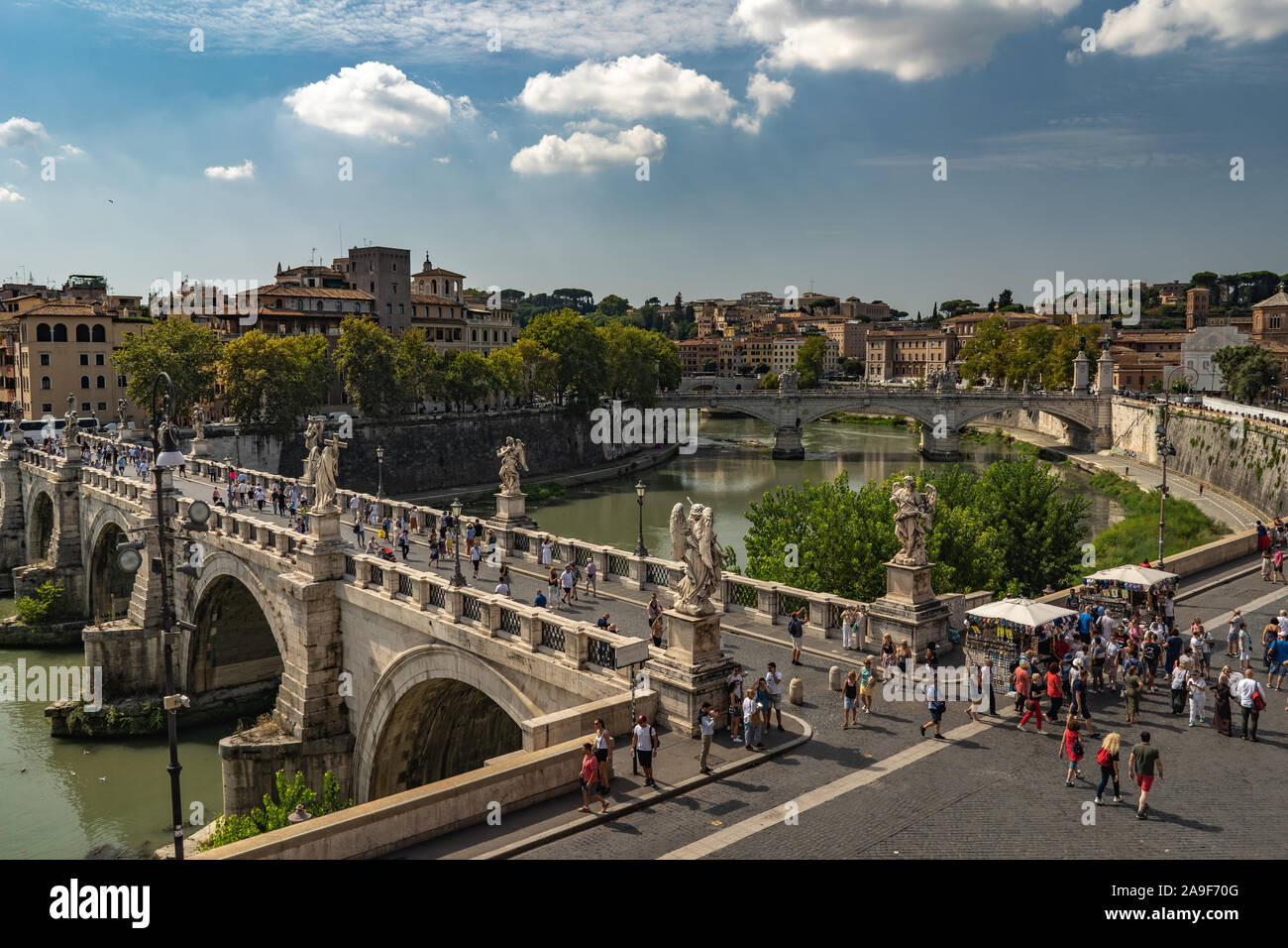Beautiful view from Castel Sant'Angelo on the bridge, people walking on it and Tiber river. Beautiful sunny weather in Rome, fairytale look like. Stock Photo