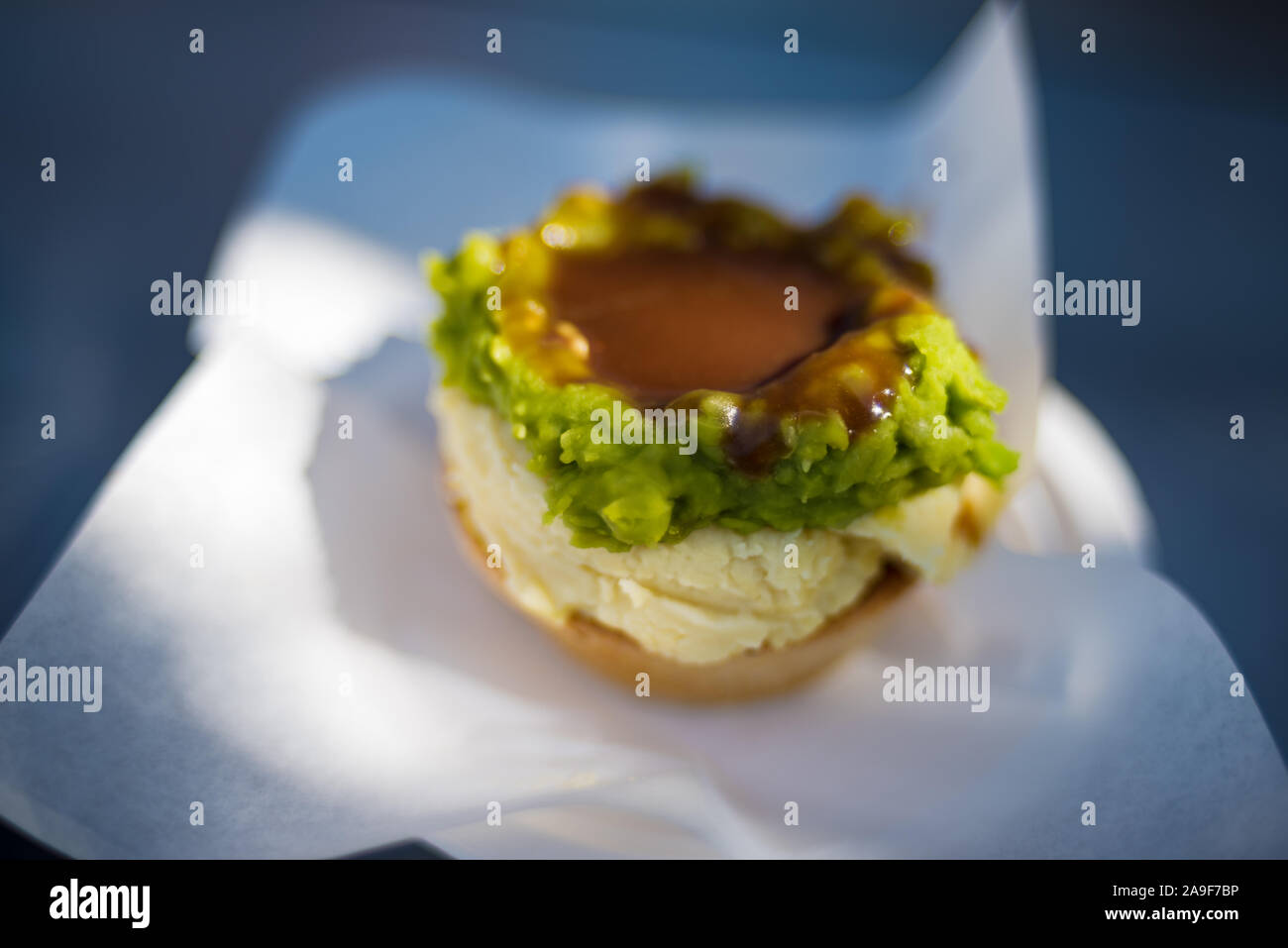 Australian traditional meat pie with mashed potatoes, green peas and gravy in pastry case Stock