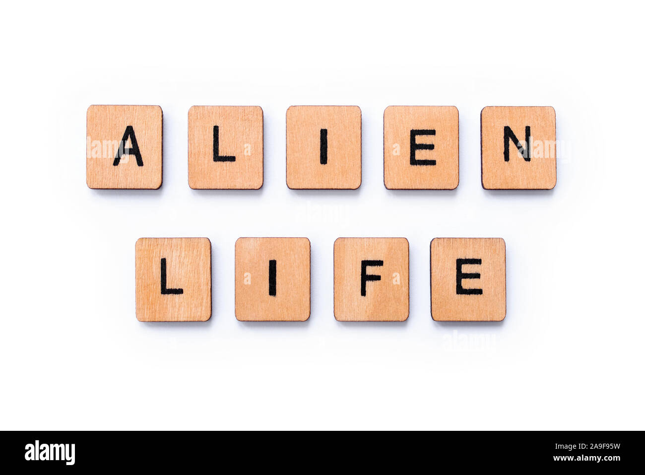 The phrase ALIEN LIFE, spelt with wooden letter tiles over a white background. Stock Photo