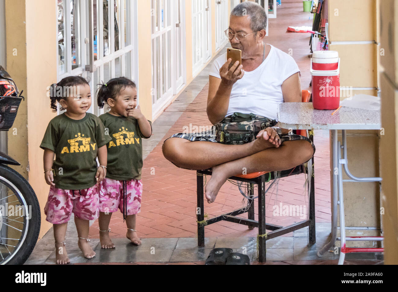 Bangkok, Thailand - 25th September 2018: Grandfather singing the National Anthem to a pair of twin girls. Thais are very nationalistic. Stock Photo