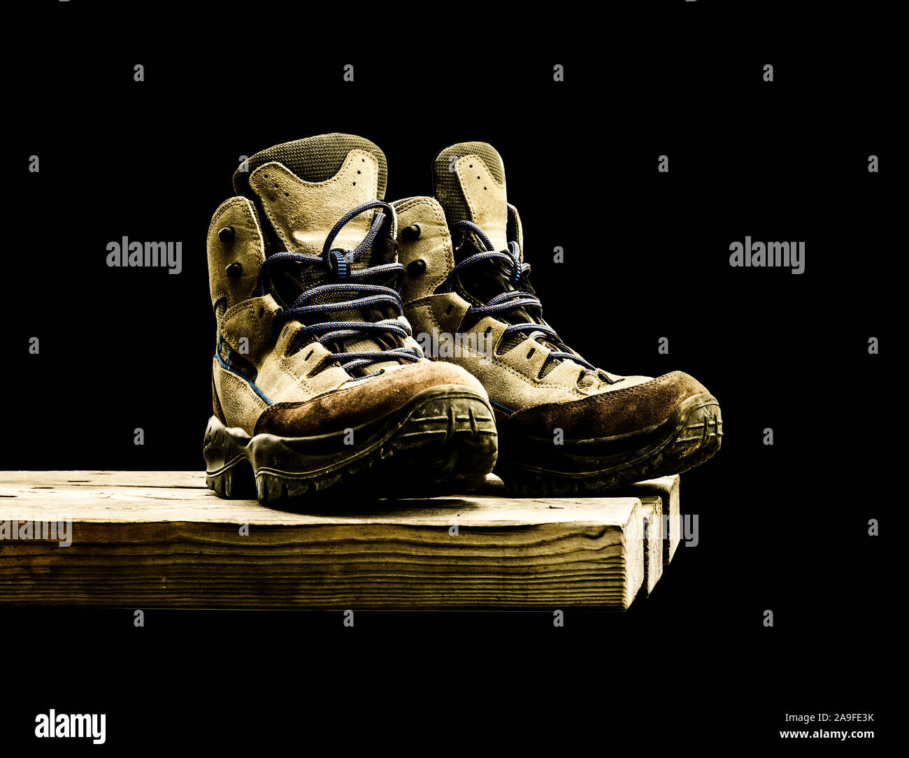 Hiking boots on wooden board against black background Stock Photo