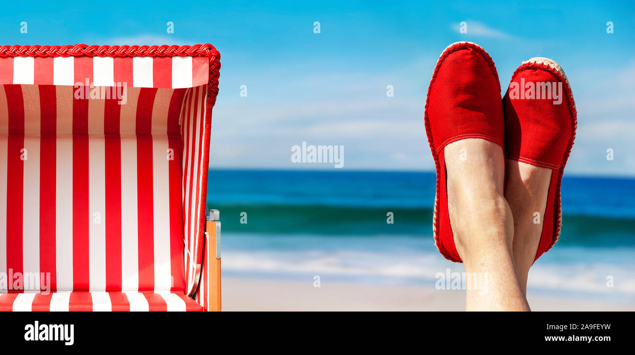 Legs with red cloth shoes in front of beach and sea Stock Photo