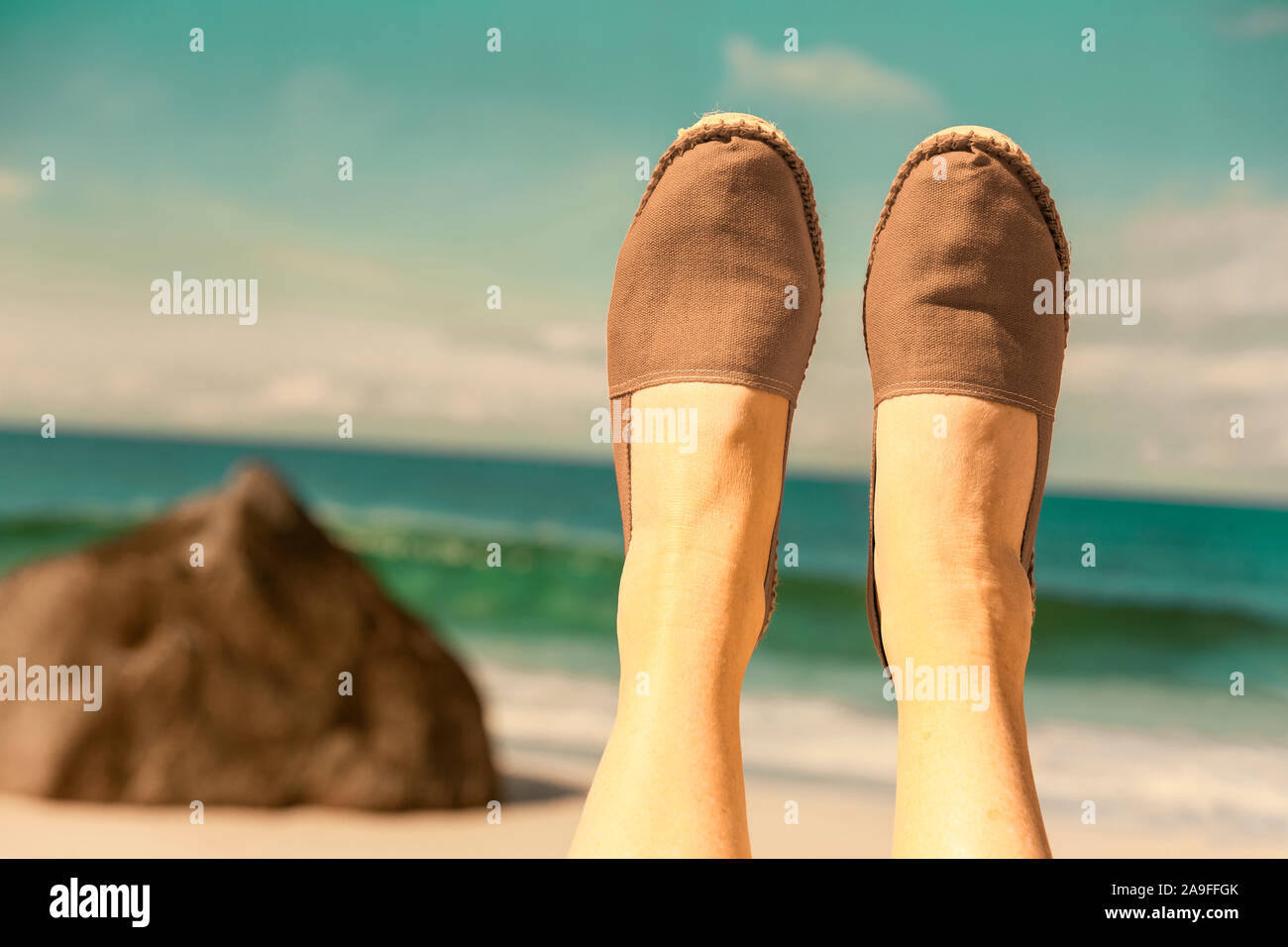 Legs with espadrilles in beige in front of water Stock Photo