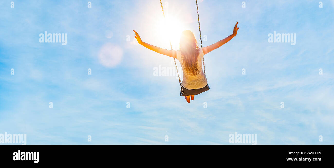 Woman on a swing with blue sky in the back light Stock Photo