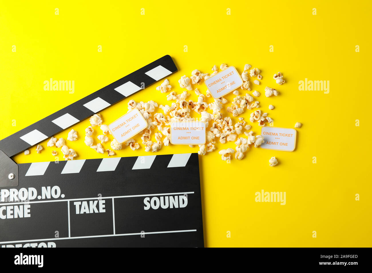 Flat lay composition with clapperboard, popcorn and tickets on yellow background Stock Photo