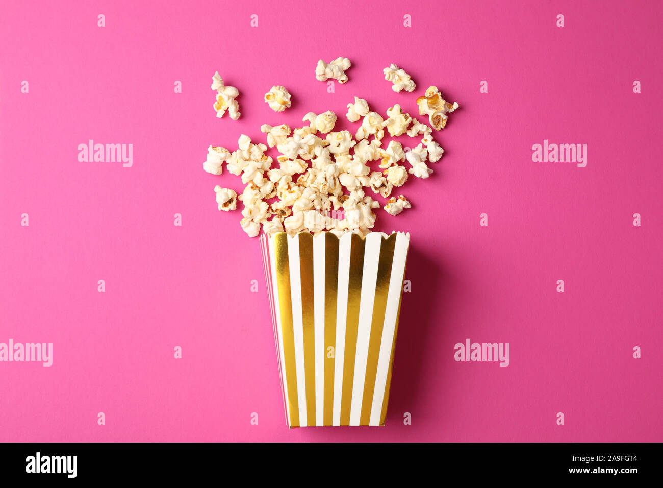 Flat lay composition with striped box and popcorn on color background Stock Photo
