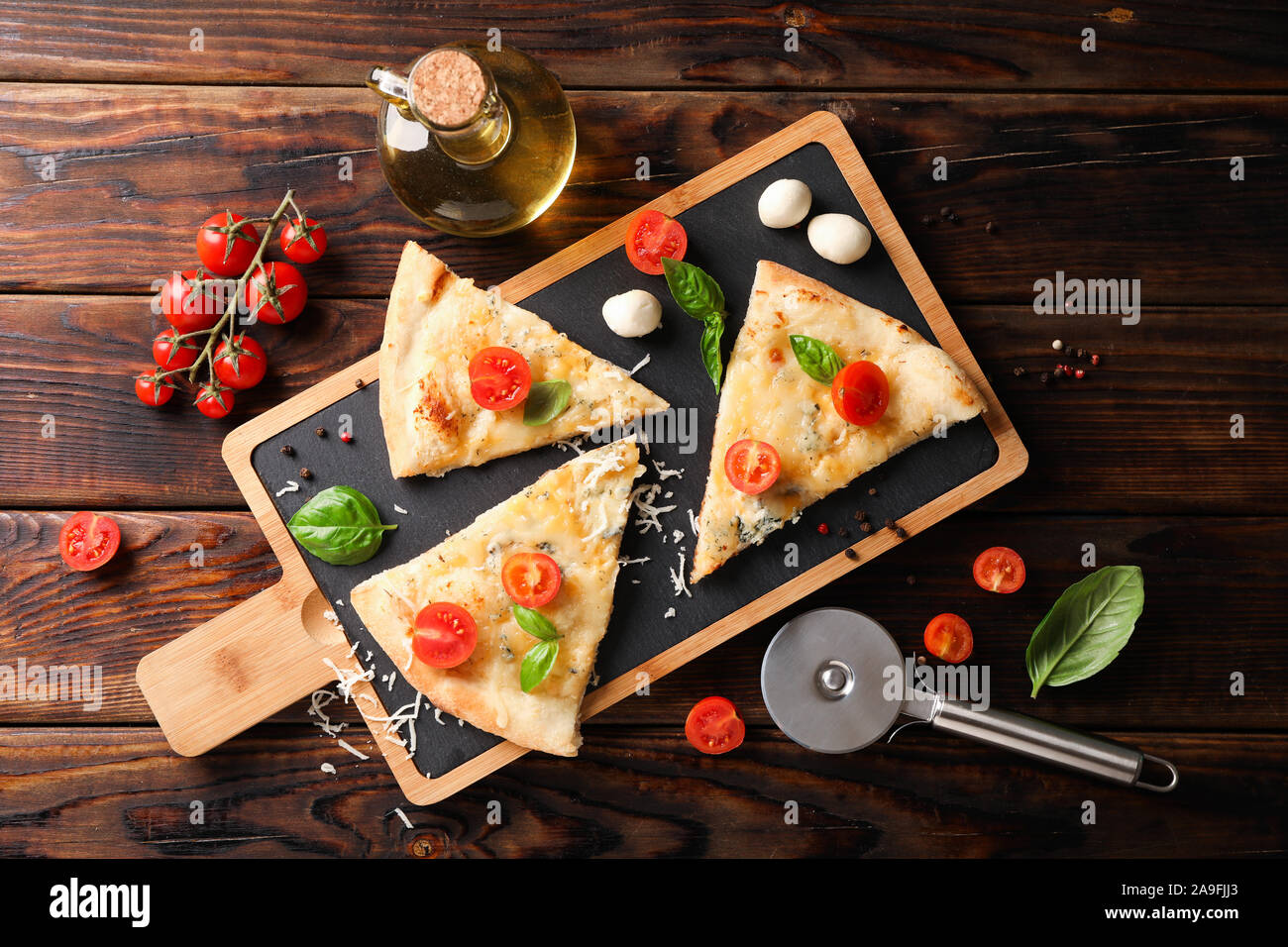 Pieces of pizza and ingredients on wooden background, top view Stock Photo