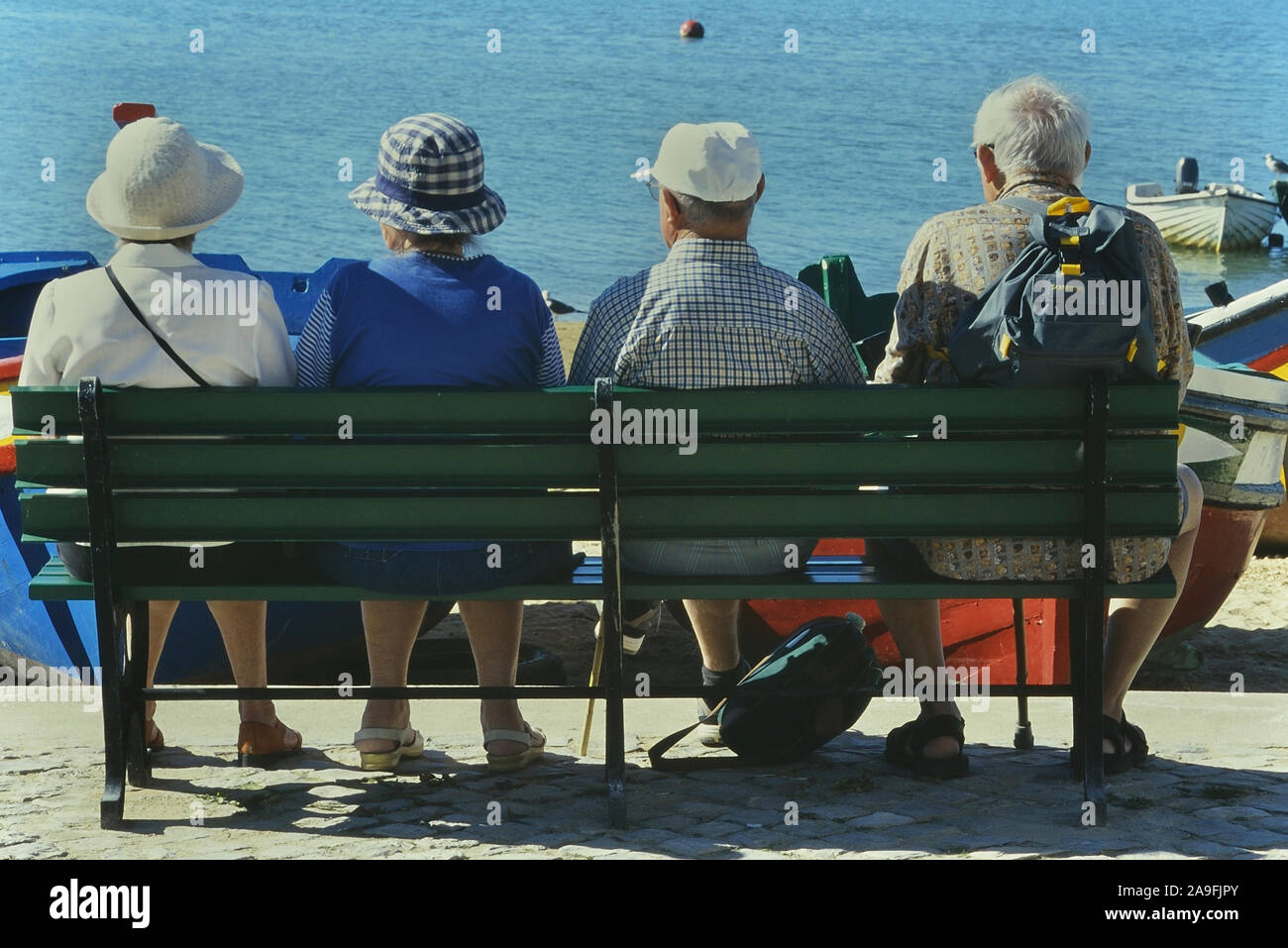 Mature adults sitting on a public bench, Alvor, Algarve, Portugal Stock Photo