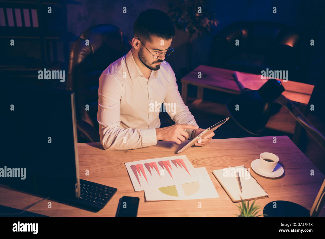 Photo of serious confident sales manager working at late night to manage to finish all work on time comparing income of company and searching for Stock Photo