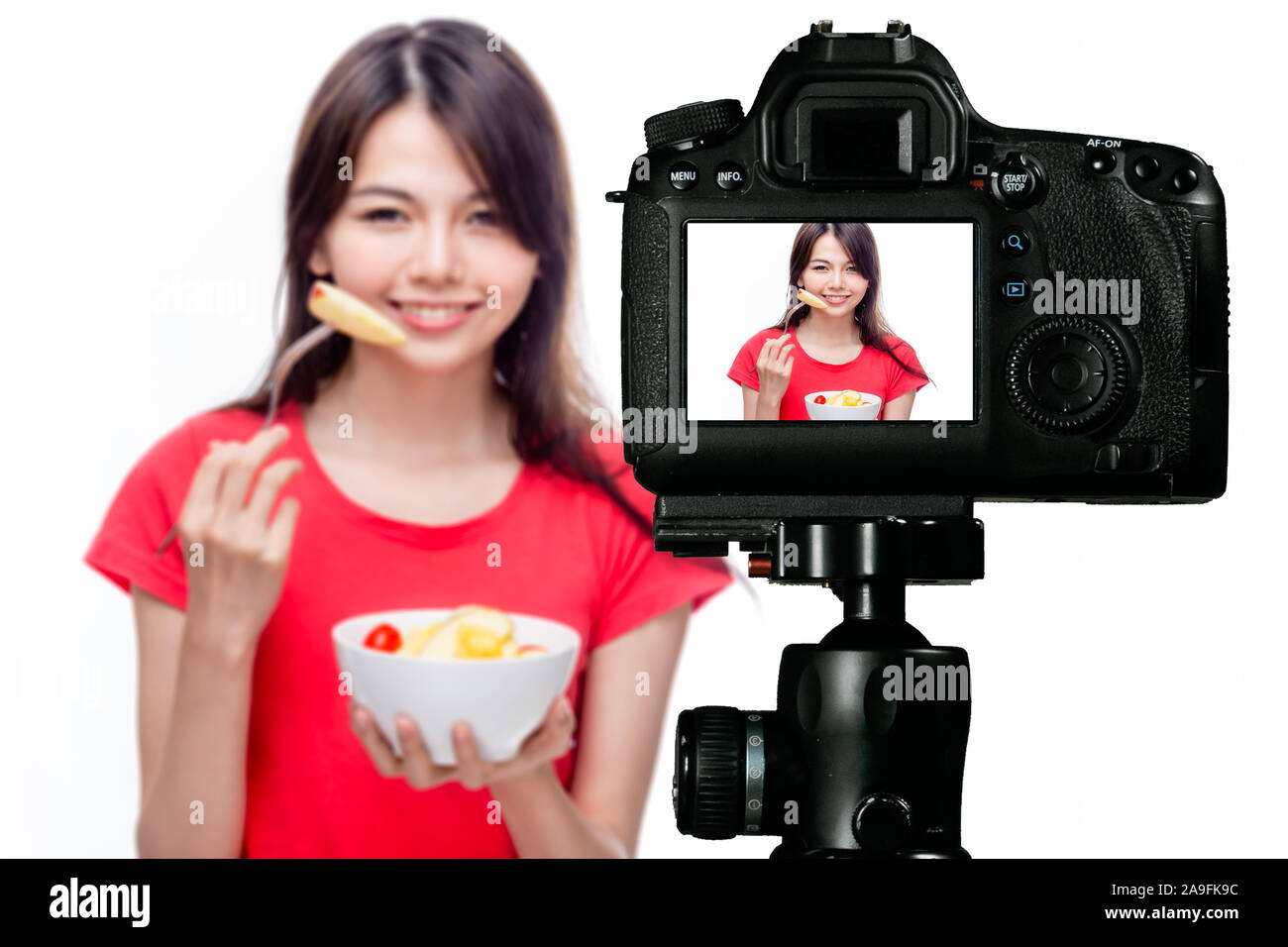 Asian food vlogger with fruit salad behind camera, social media production concept Stock Photo