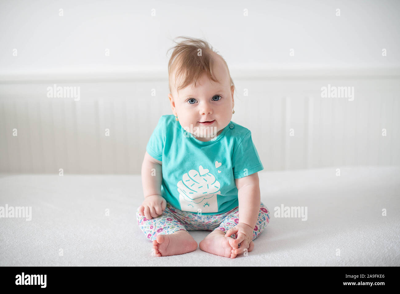 Portrait of adorable Caucasian baby girl with blue eyes, looking at the camera calmly, with curiosity, interactivity or inquisitiveness Stock Photo