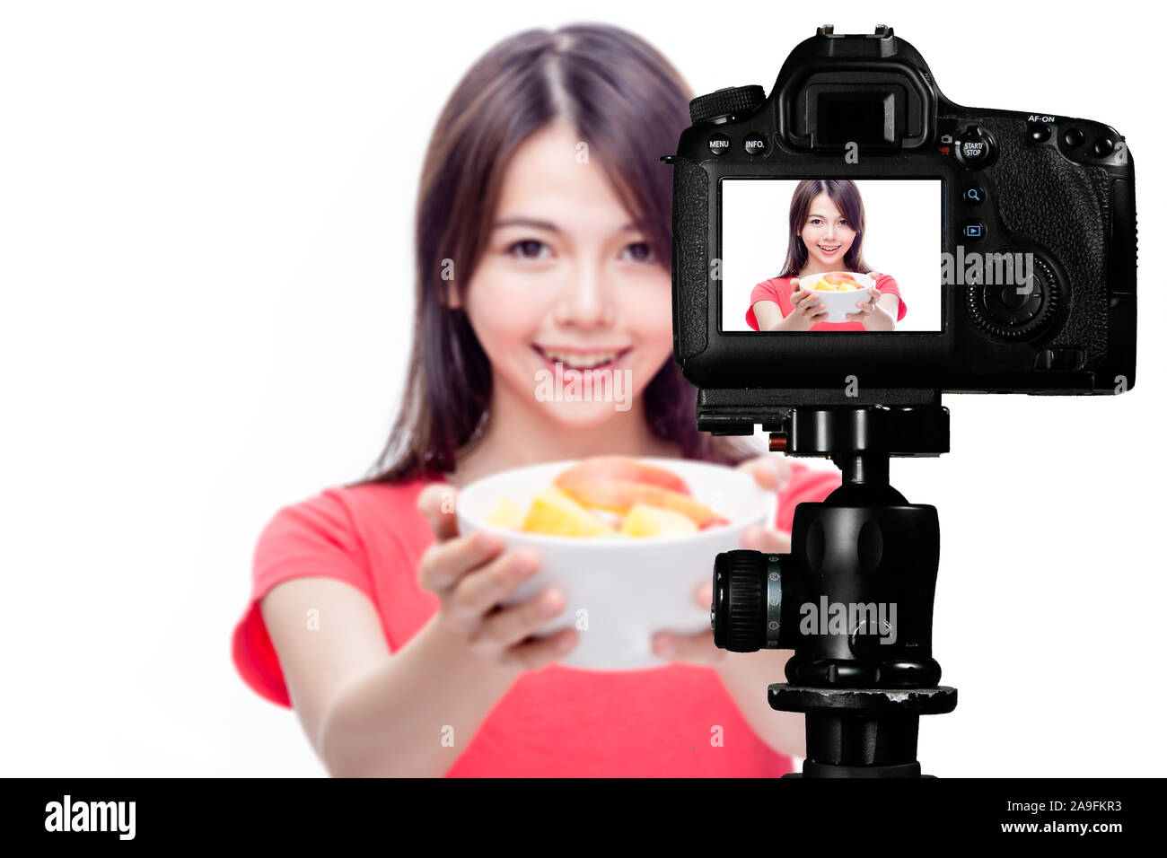 Asian food vlogger with fruit salad behind camera, social media production concept Stock Photo