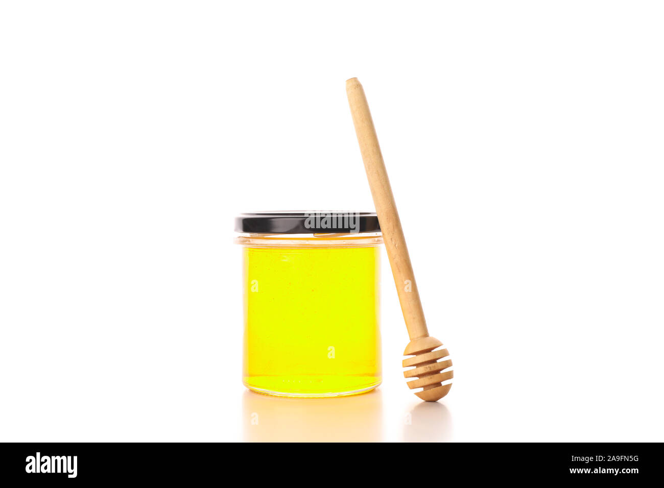 Glass jar with honey and dipper isolated on white background Stock