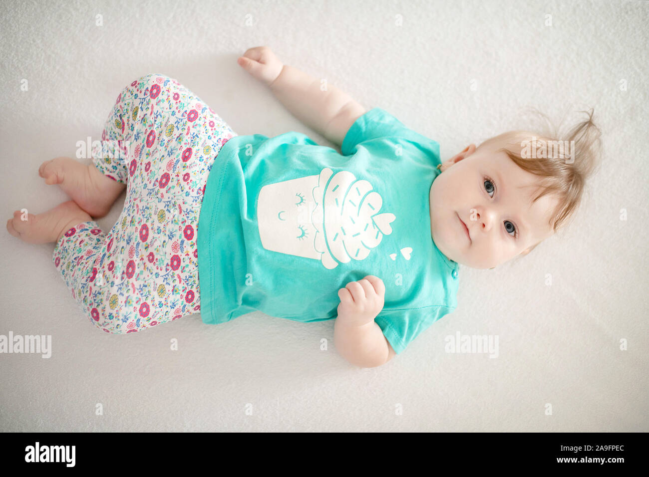 Portrait of adorable baby girl with blue eyes and cute hair looking at the camera calmly with curiosity; cute baby facial expressions, family concepts Stock Photo