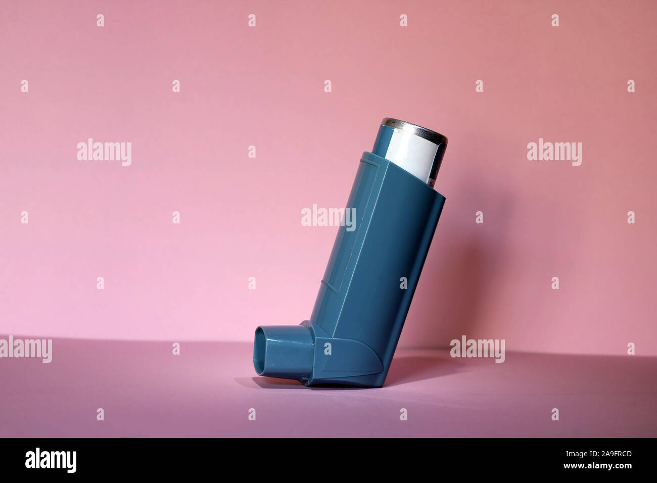 Blue asthma inhaler on a pink background. Pharmaceutical product to prevent and treat an asthma attack. Stock Photo