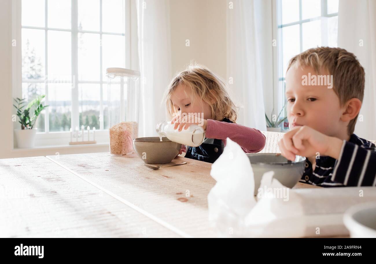 brother and sister eating breakfast at home before school Stock Photo