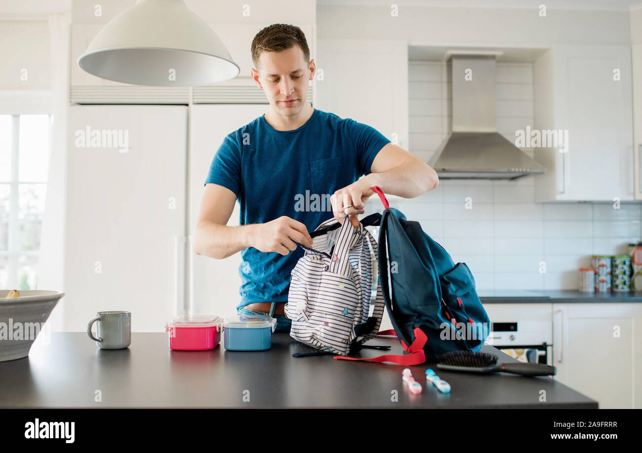 father packing his kids school bags in the morning at home Stock Photo