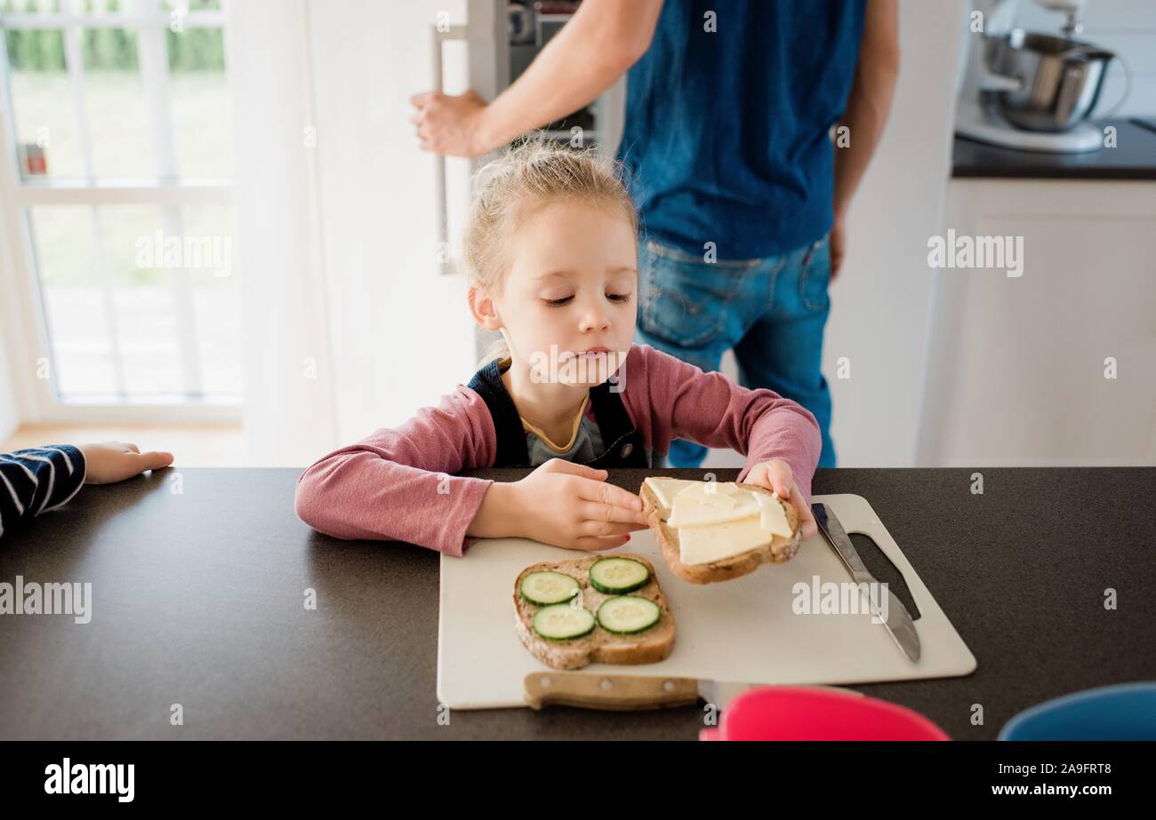 young girl helping her dad make lunch at home before school Stock Photo