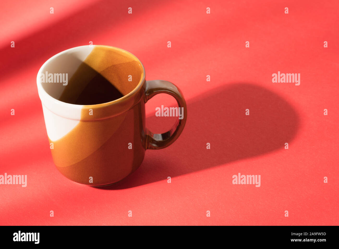 Empty brown cup on red table. Abstract coffee theme still life Stock Photo
