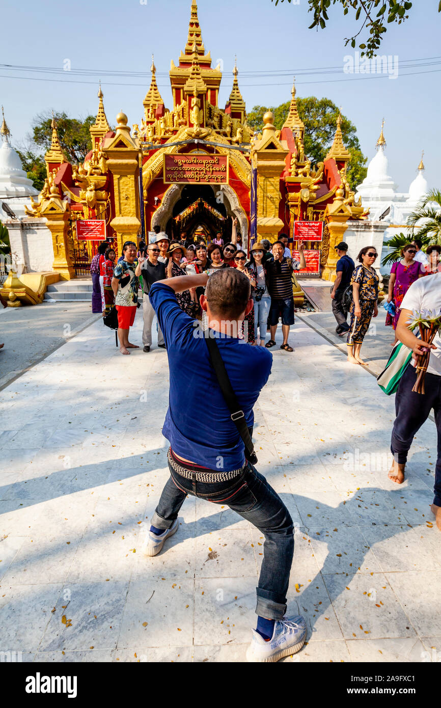 A Man Takes A Photo Of A Tour Group Outside The Kuthodaw Pagoda, Mandalay, Myanmar. Stock Photo