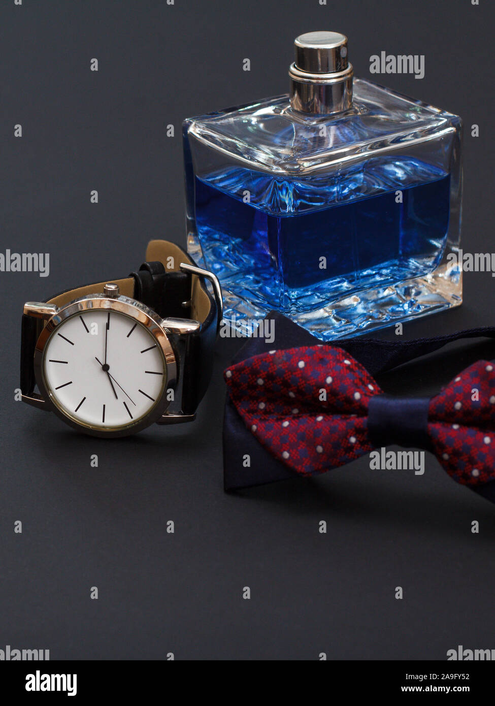 Watch with a black leather strap, cologne for men and bow tie on black ...