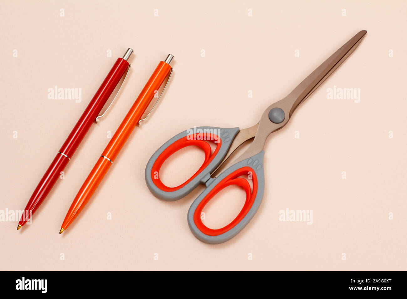 Two pens and scissors on a beige background. Top view Stock Photo - Alamy