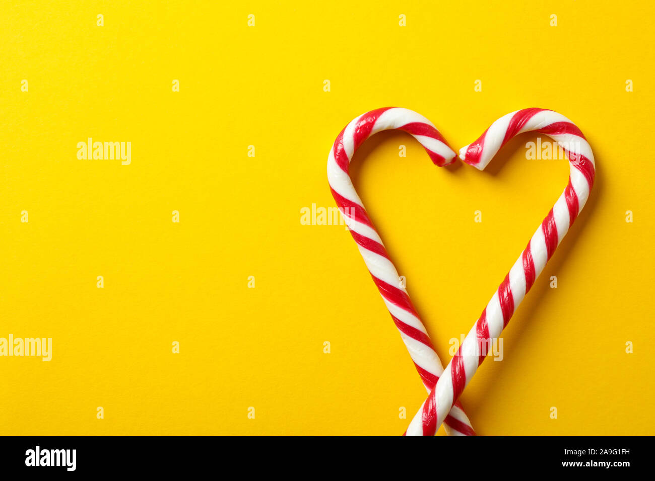 Sweet candy canes on yellow background, space for text Stock Photo