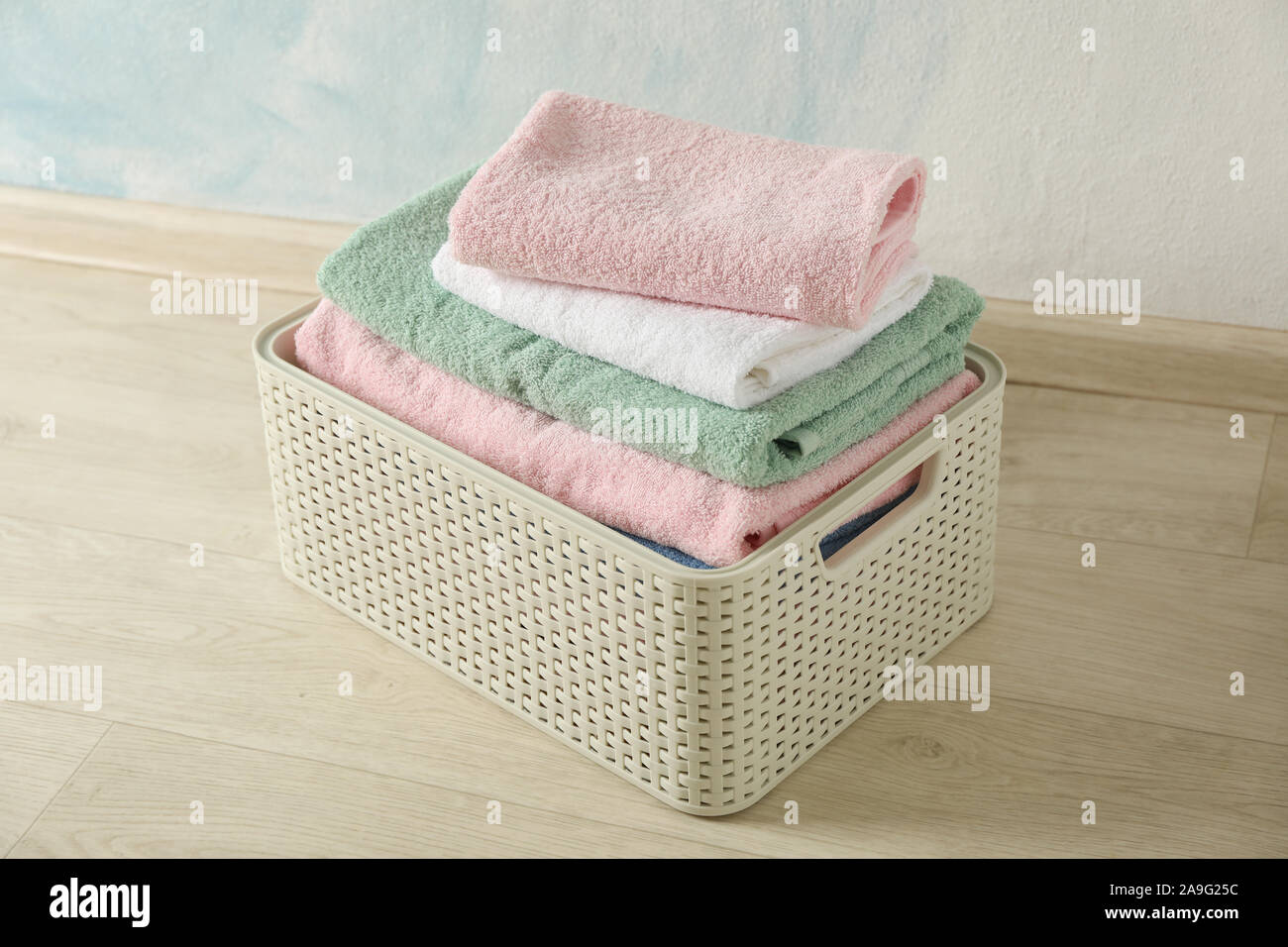 Basket with clean laundry on textured floor, space for text Stock Photo