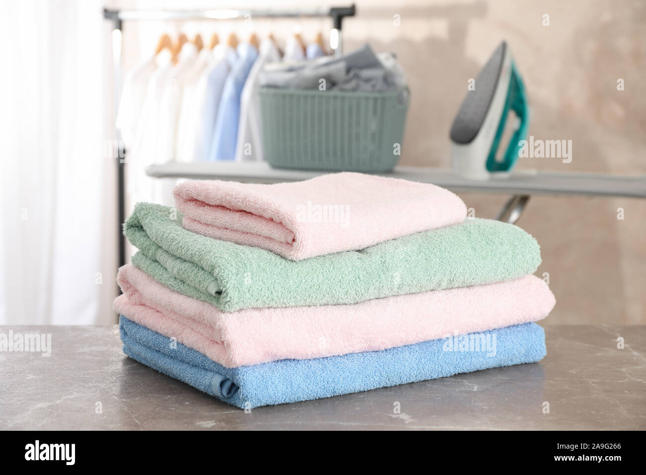 Stack of clean towels on ironing board, space for text Stock Photo