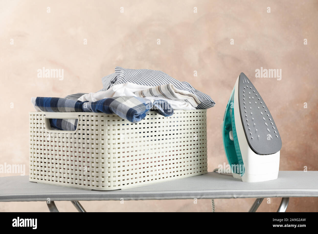 Basket with clean laundry and iron on ironing board, space for text Stock Photo