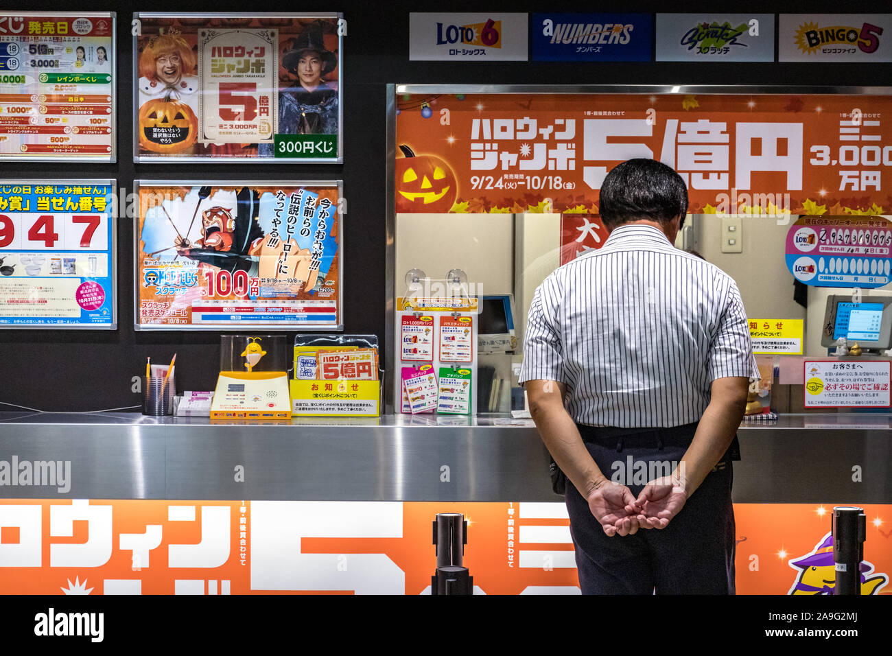Japanese man with hands on back looking lottery tickets at the Hiroshima Bus Center in Japan. Stock Photo