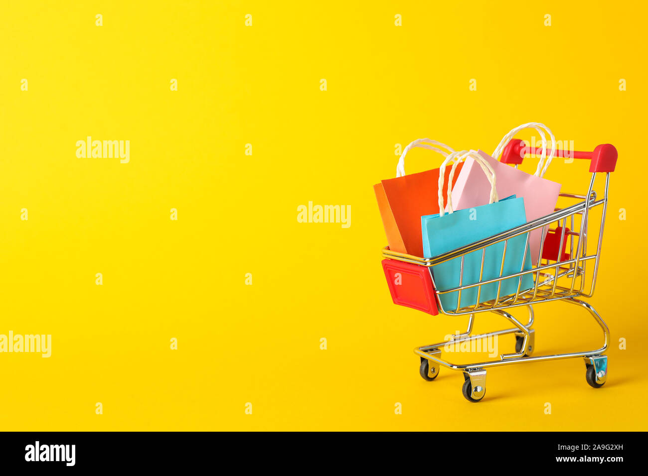 Download Small Shopping Cart With Paper Bags On Yellow Background Space For Text Stock Photo Alamy Yellowimages Mockups