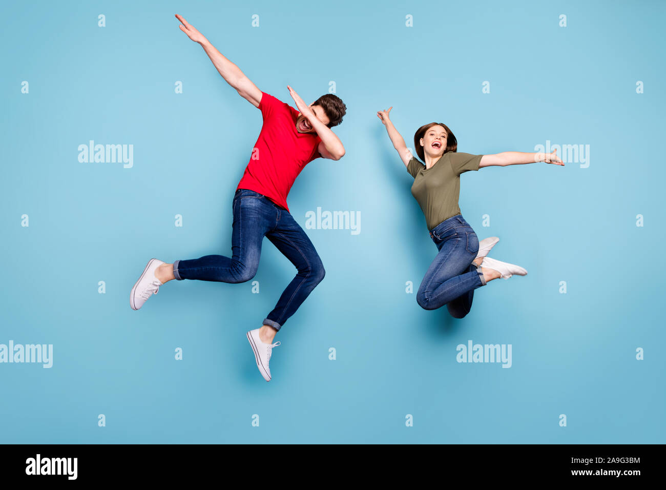 Full size photo of funky crazy two married people students fun jump man perform dab dancers woman raise hands wear green red t-shirt denim jeans Stock Photo