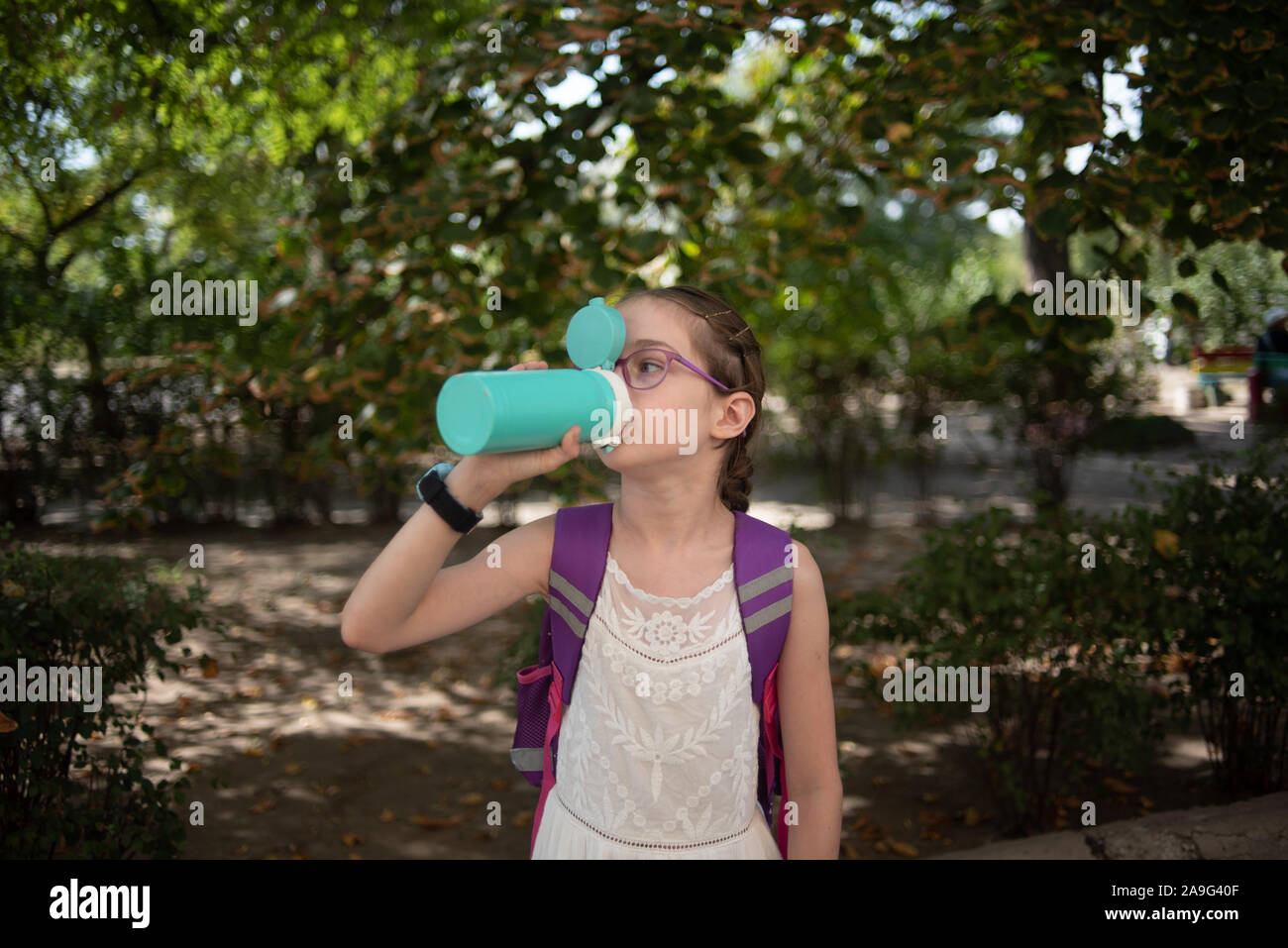 girl with cup. schoolgirl girl in glasses drinks water from a thermos or thermomug.A schoolgirl drinks tea, juice or water from a thermal cup or therm Stock Photo
