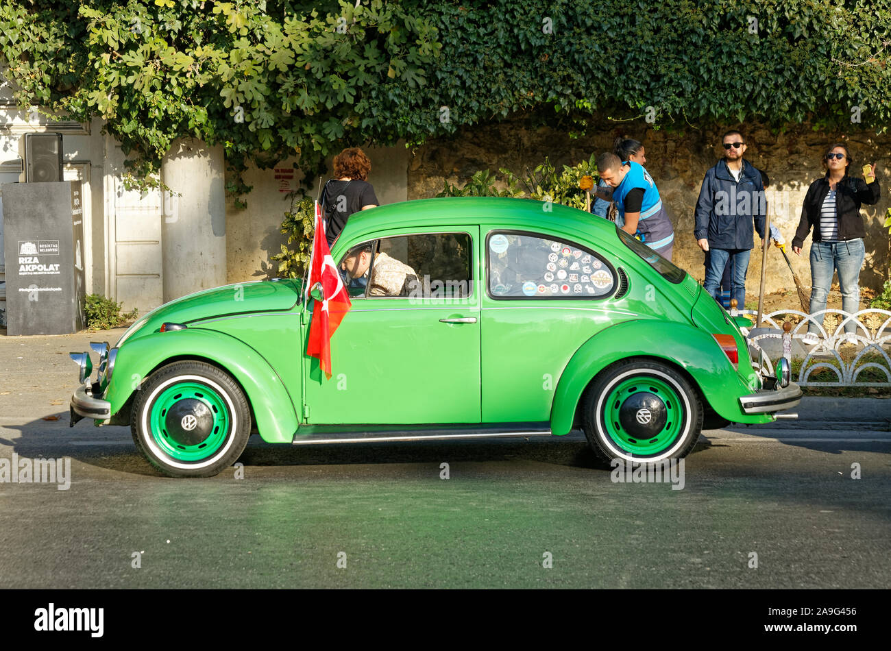 Side view of Green Classical Volkswagen Beetle parked in Dolmabahce Street. Volkswagen emblem on the on the rims. Turkish Flag hanged to left mirror. Stock Photo