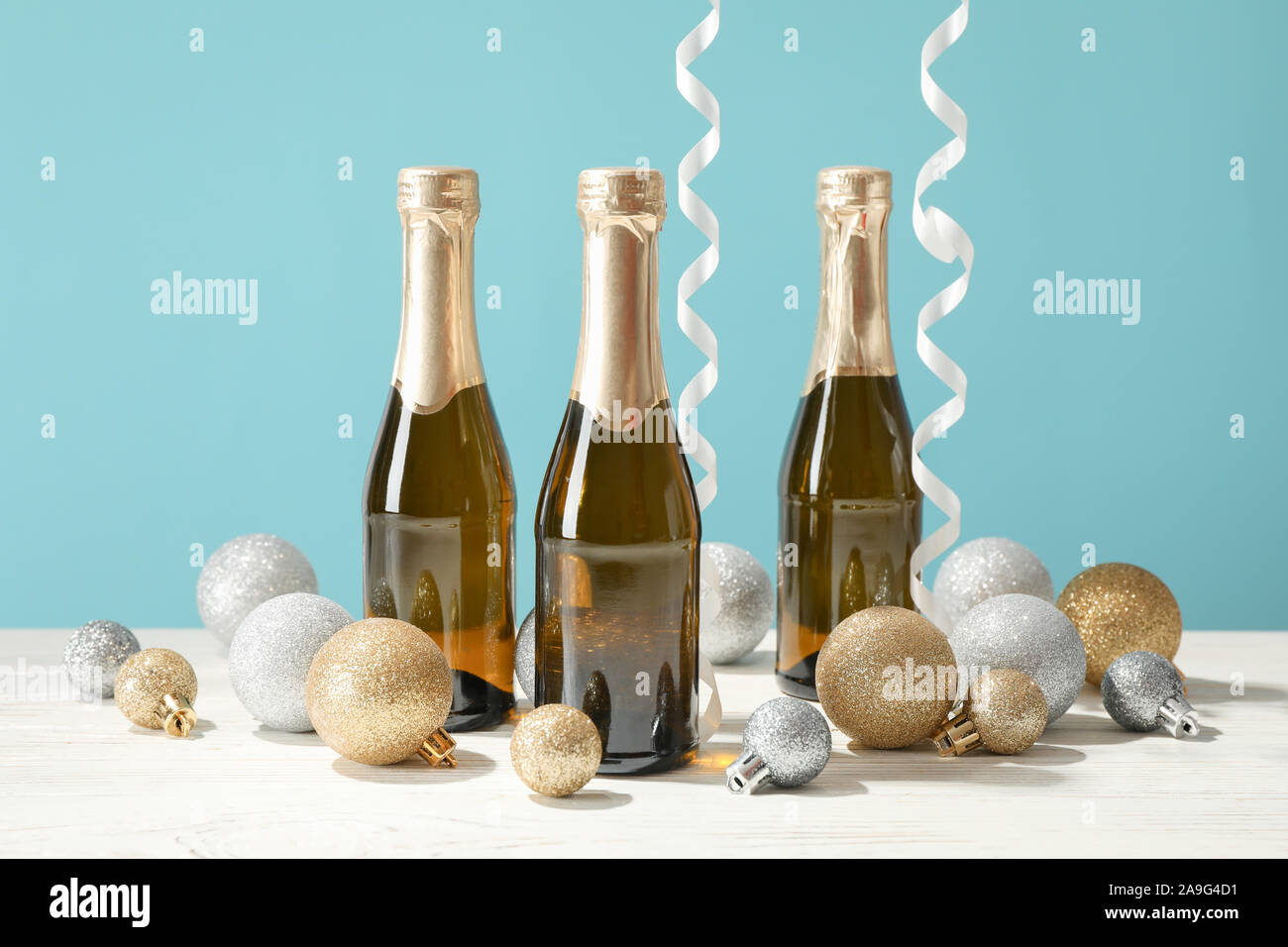 Baubles and champagne mini bottles against blue background, space for text Stock Photo