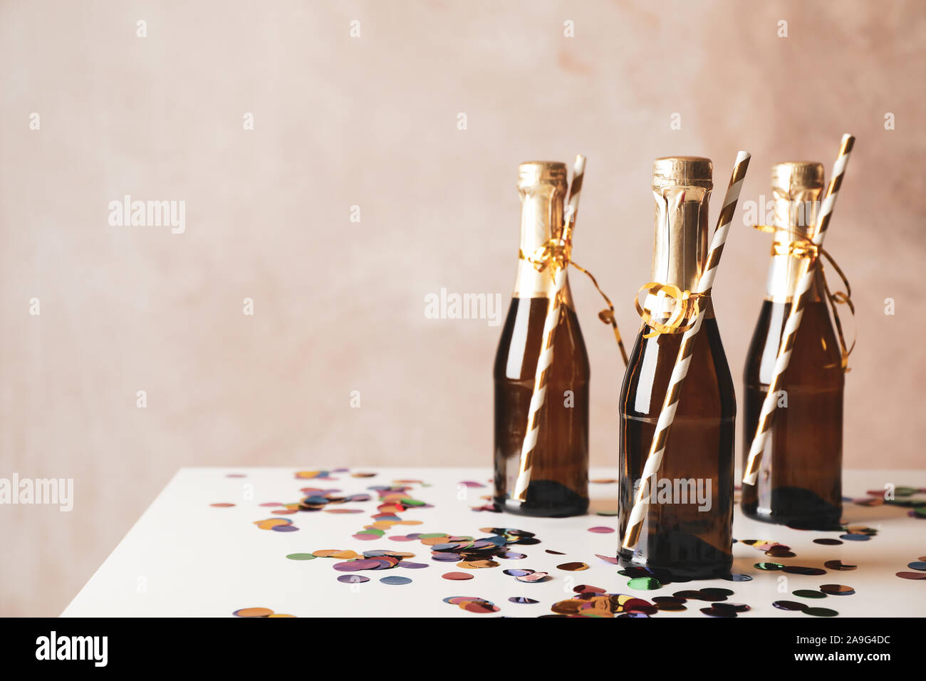 Mini champagne bottles with straws on decorated background, copy space Stock Photo