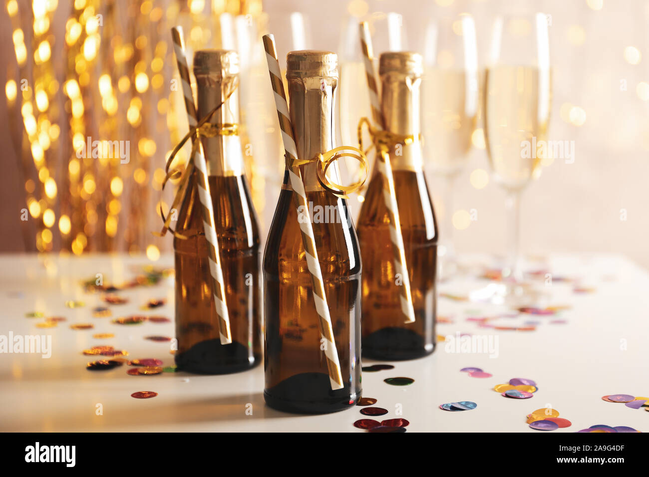 Champagne glasses and mini bottles on decorated background, space for text Stock Photo