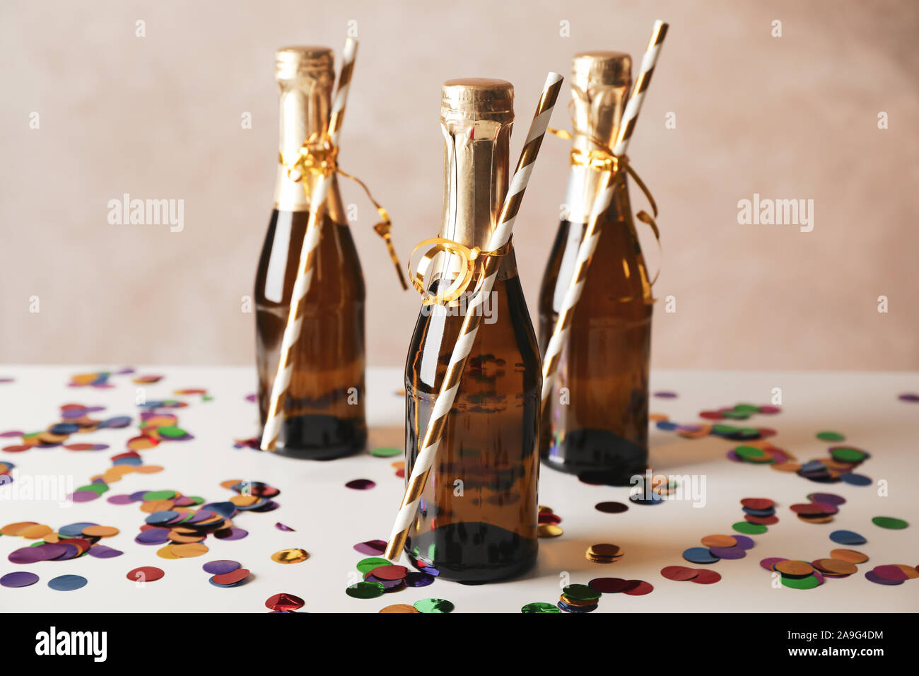 Mini champagne bottles with straws on decorated background, close up Stock Photo