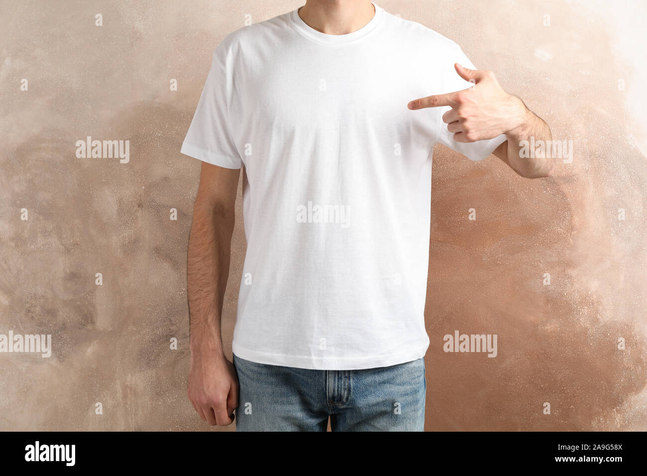 Men in blank white t-shirt against brown background, space for text