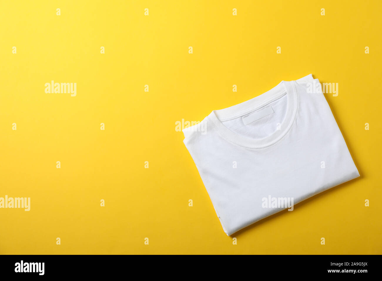 Folded blank white t-shirt on yellow 