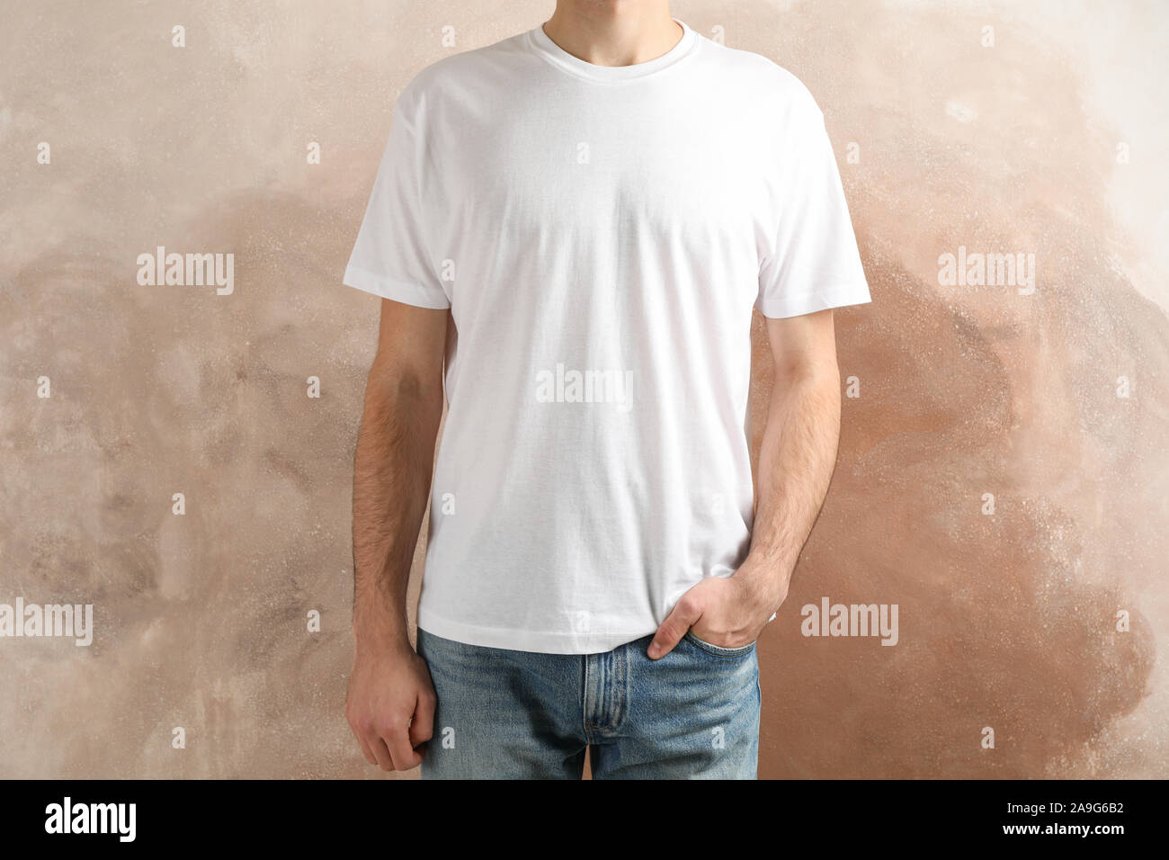 Men in blank white t-shirt against brown background, space for text