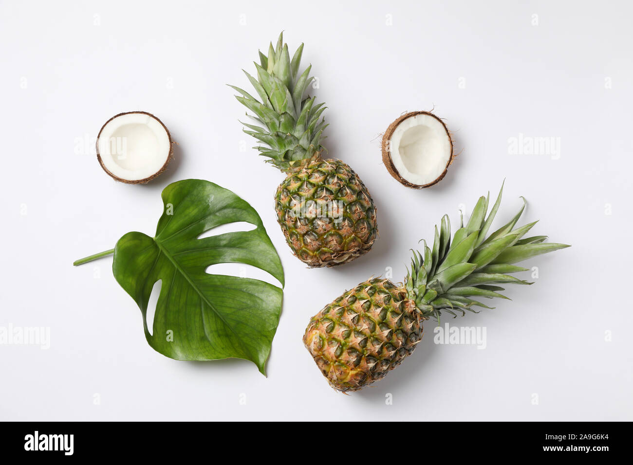 Pineapples, coconuts and palm leaves on white background, top view Stock Photo