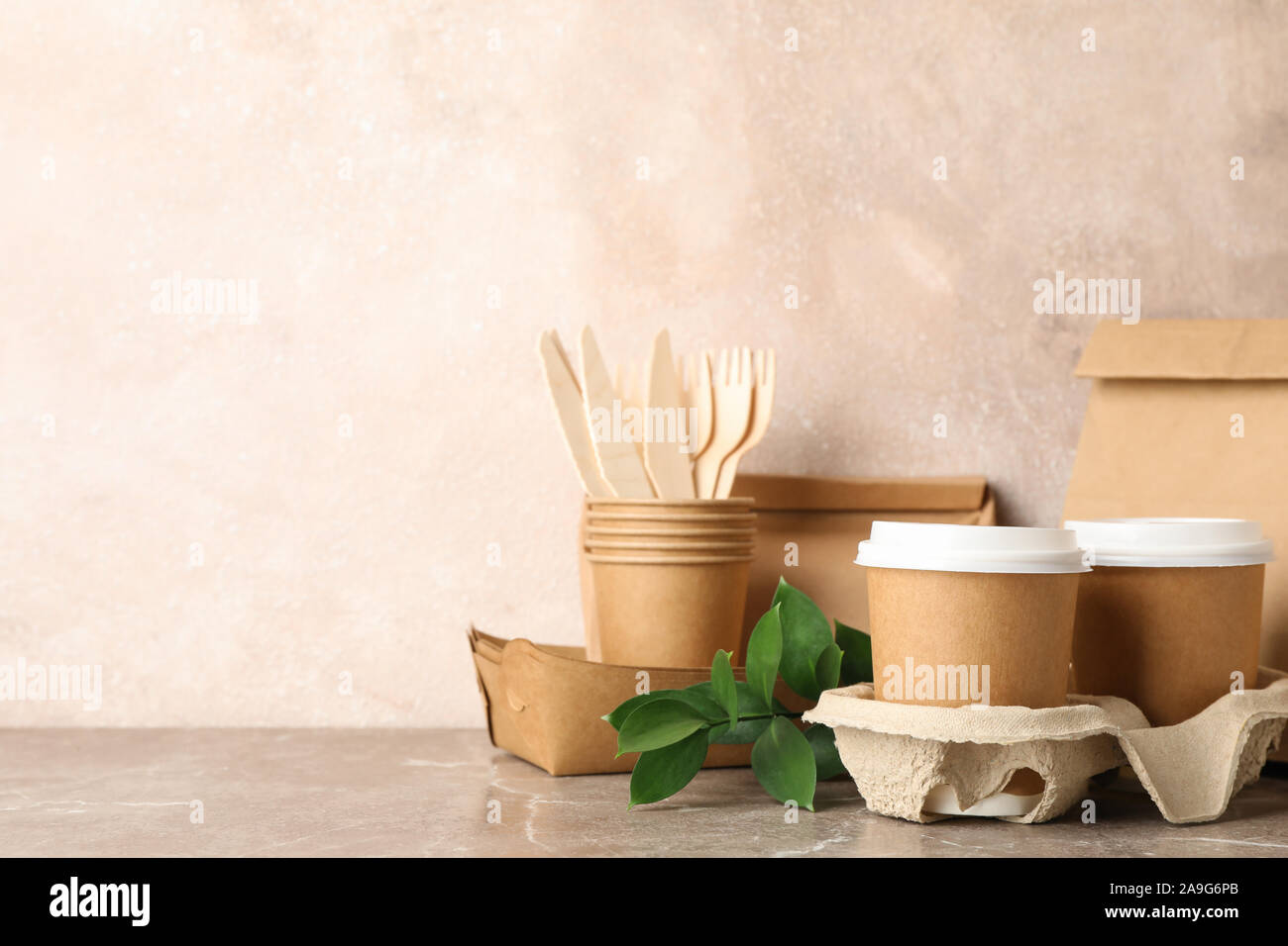 Eco - friendly tableware and paper bag on grey table, space for text ...