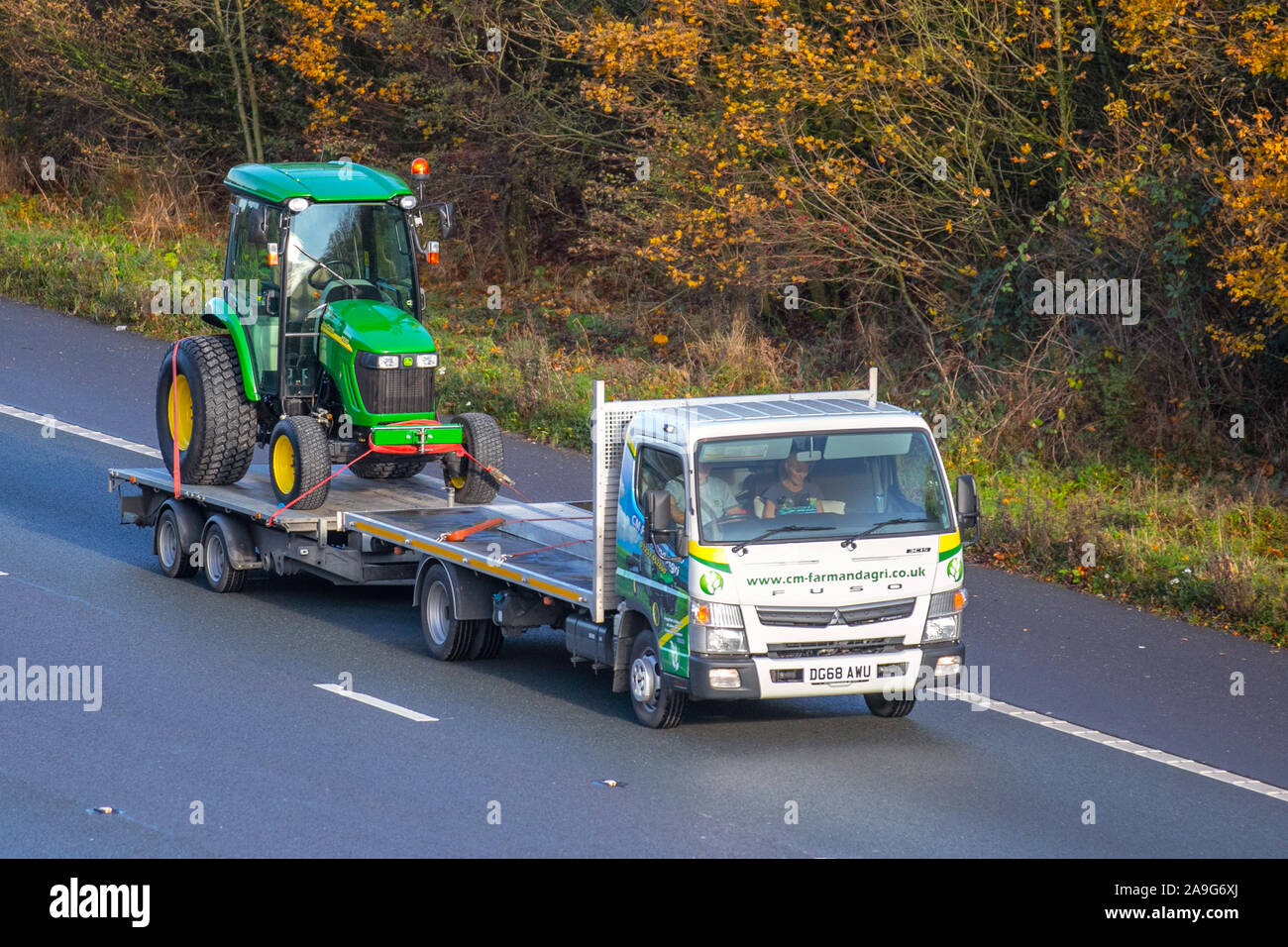2018 white Mitsubishi Fuso Canter 3c15 38 Auto transporting JohnDeere 4520; Haulage delivery trucks, lorry, transportation, farm tractor on truck, cargo, vehicle, delivery, commercial transport, industry, on the M61 at Chorley, UK Stock Photo
