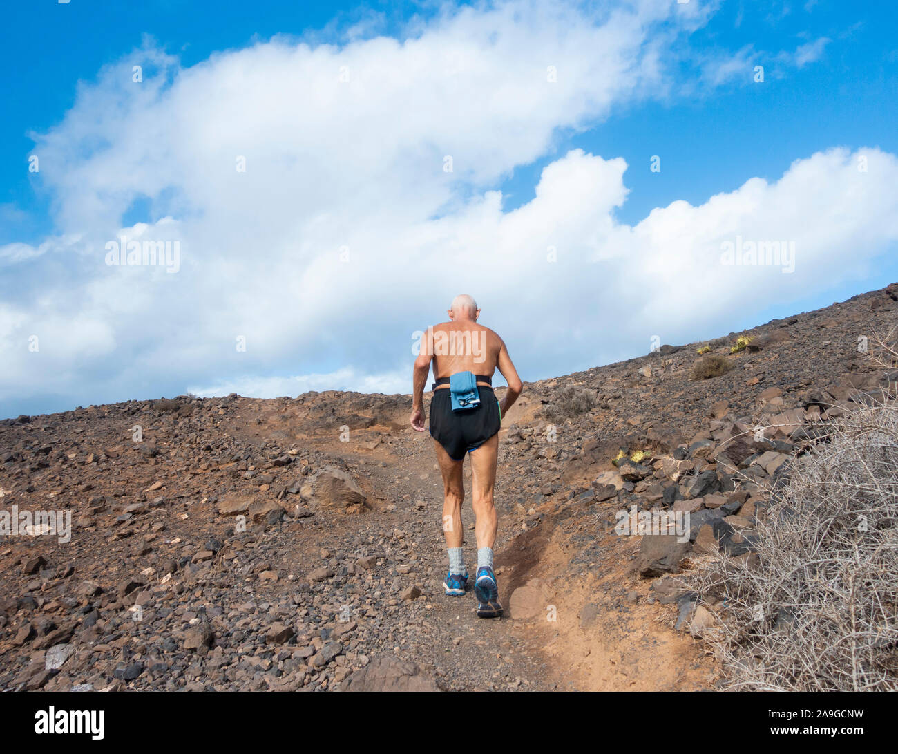 Rear view of elderly man, pensioner trail running. Stock Photo