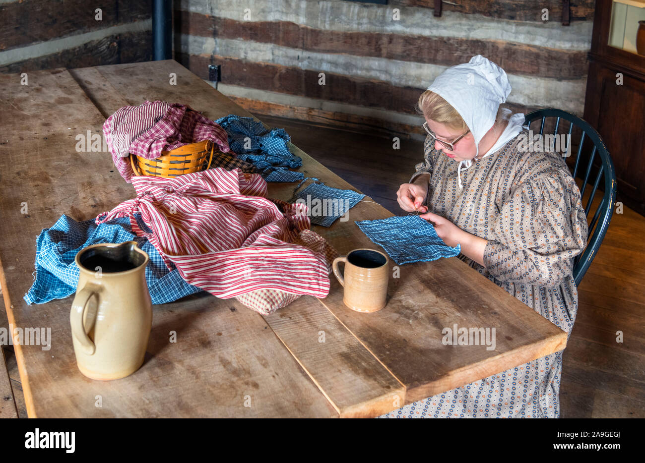 Re-enactor, in early 19th century dress, sewing inside the Newcom Tavern, Carillon Historical Park, Dayton, Ohio, USA Stock Photo