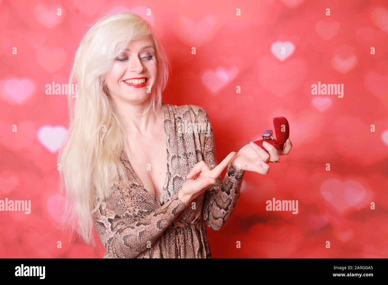 Female holding a box with a ring on red studio background Stock Photo