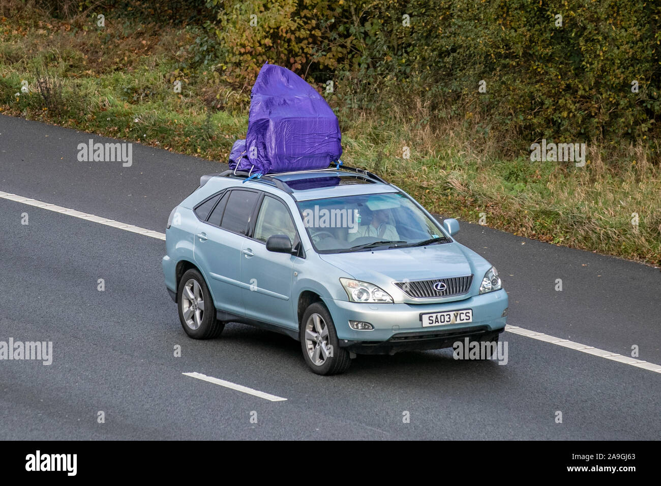 Projecting dangerous load being carried by 2003 blue Lexus Rx300 SE Auto; UK Vehicular traffic, transport, modern vehicles, saloon cars, south-bound on the 3 lane M61 motorway highway. Stock Photo