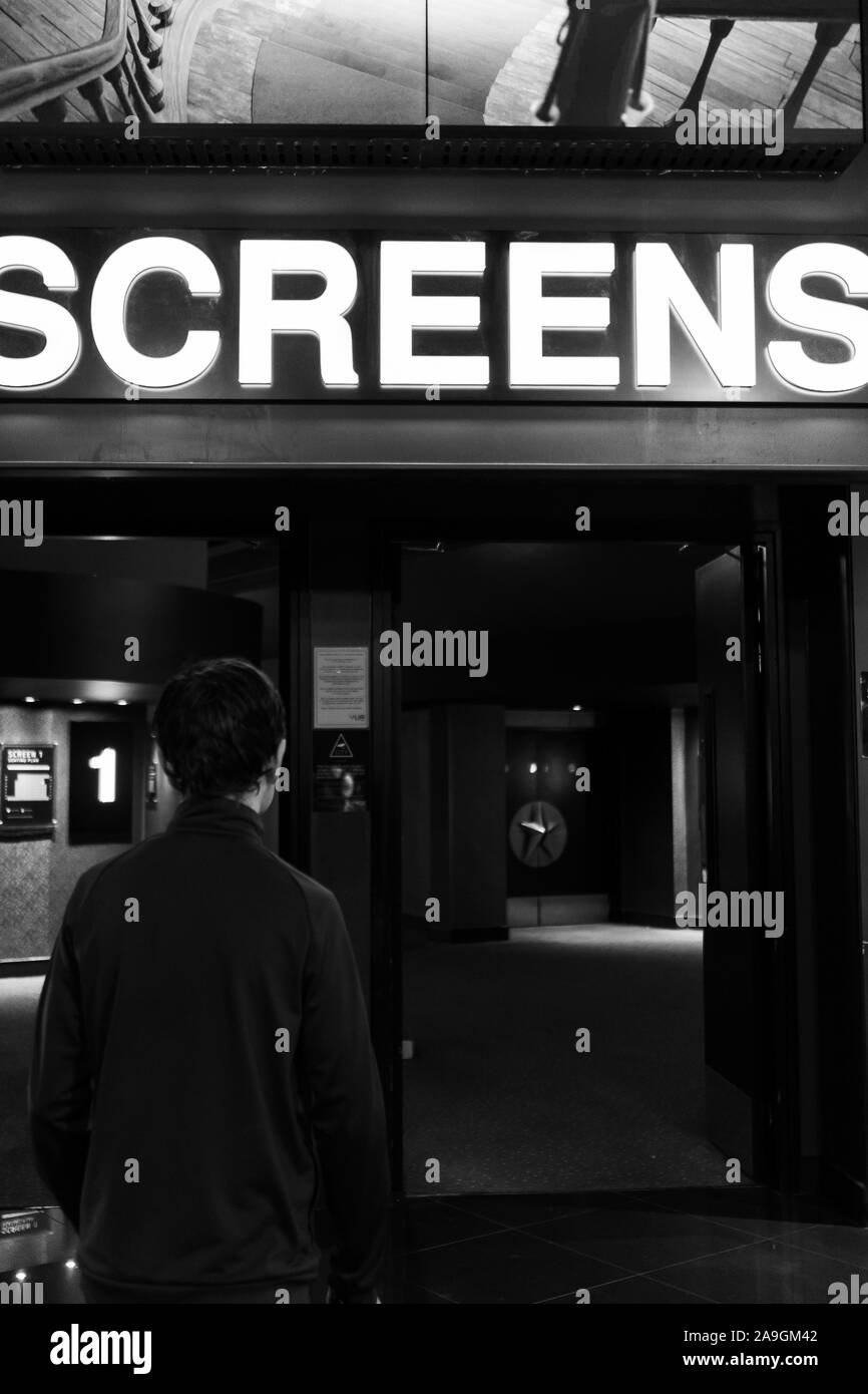A young boy with ADHD, autism, Asperger syndrome walks towards the cinema screens at VUE in Newcastle to watch a movie, film Stock Photo